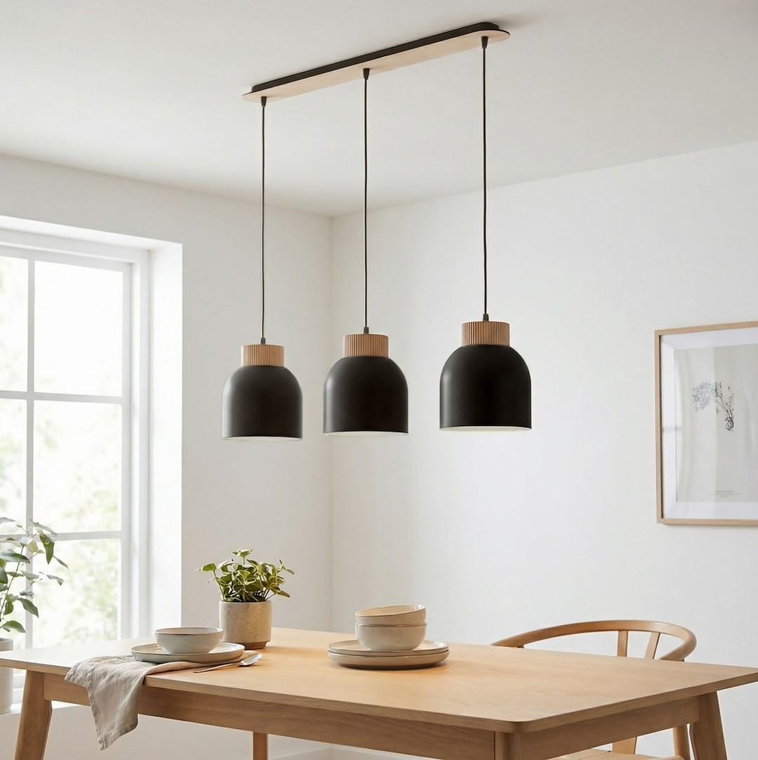 Lampa wisząca Vigo 3xE27 w kolorze czarnym z drewnianymi detalami. Ułożona poziomo, zawieszona na czarnych przewodach. Widoczna w aranżacji jadalni, nad drewnianym stołem z porcelanowymi talerzami i doniczką rośliny.