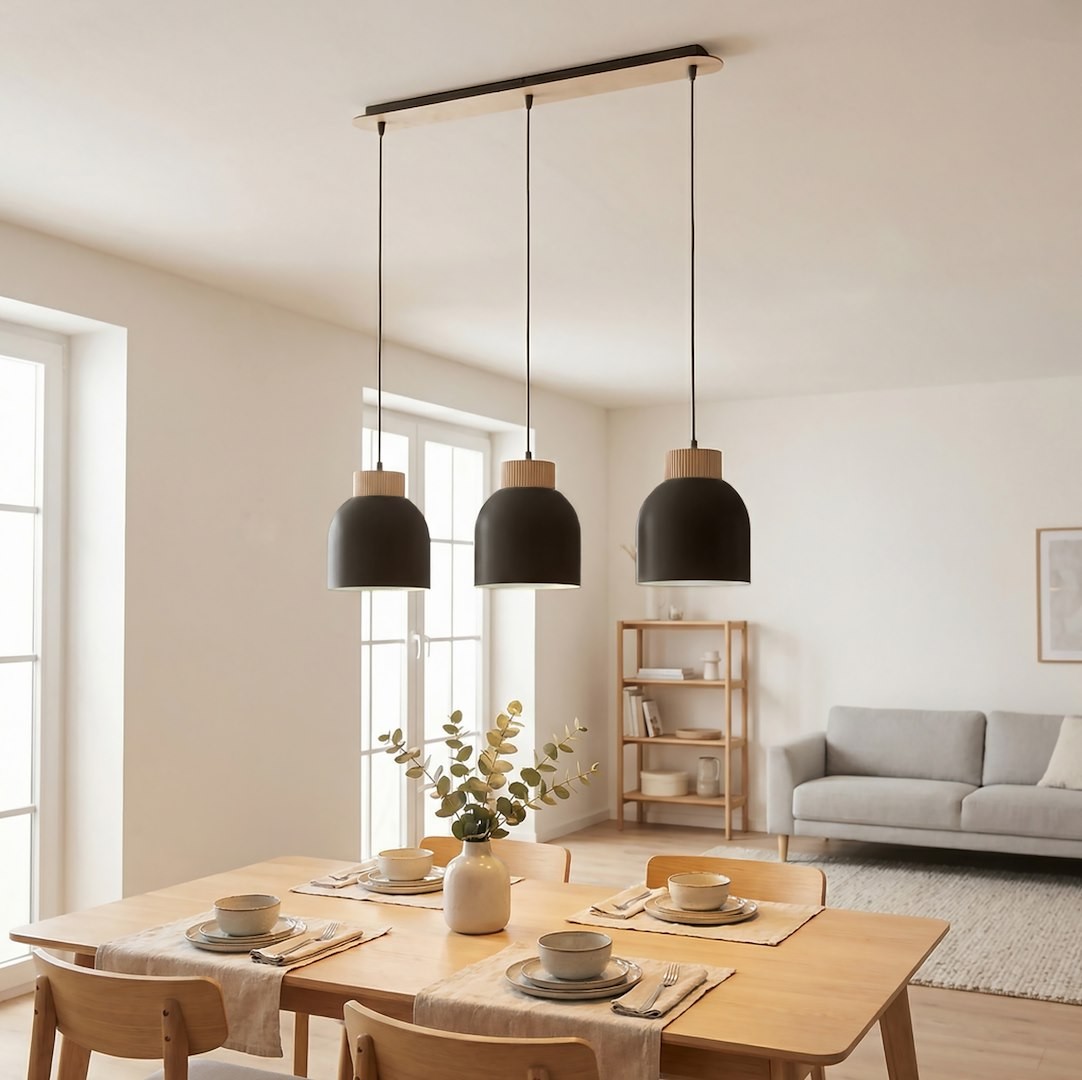 Lampa wisząca Vigo 3xE27 w kolorze czarnym z drewnianymi detalami, zawieszona na długich przewodach. Trzy klosze w kształcie dzwonu, w aranżacji jadalni z drewnianym stołem i krzesłami. Jasne, neutralne tło z oknami i regałem.