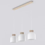 Lampa wisząca Vigo z trzema białymi kloszami zawieszonymi na cienkich linkach. Klosze mają drewno w naturalnym odcieniu na górze. Całość montowana do sufitu na prostokątnej, drewnianej podstawie.