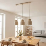 Lampa wisząca Vigo 3xE27 w kolorze mokka z trzema zaokrąglonymi kloszami. Zawieszona na prostokątnej podstawie, w otoczeniu stołu z nakryciem. Jasne tło i naturalne elementy dekoracyjne w aranżacji wnętrza.