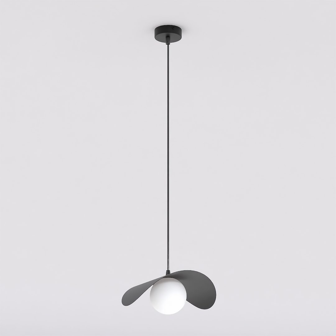 Lampa wisząca Ritual M w kolorze czarnym z jednym źródłem światła G9. Produkt ma okrągły, biały klosz otoczony dwoma asymetrycznymi, czarnymi skrzydłami. Zawieszona na cienkim, czarnym przewodzie z sufitu. Tło jasne, jednolite.