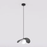 Lampa wisząca Ritual M w kolorze czarnym z jednym źródłem światła G9. Produkt ma okrągły, biały klosz otoczony dwoma asymetrycznymi, czarnymi skrzydłami. Zawieszona na cienkim, czarnym przewodzie z sufitu. Tło jasne, jednolite.