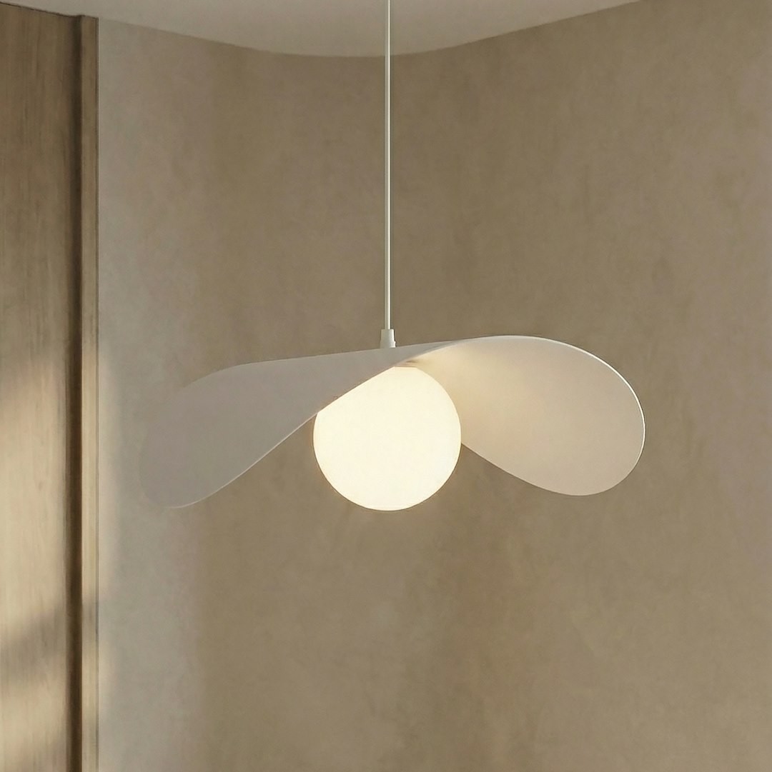 Lampa wisząca Ritual L w kolorze białym z jedną żarówką G9. Okrągła kula świetlna otoczona dwoma asymetrycznymi skrzydłami. Zawieszona na cienkim przewodzie, w minimalistycznym, nowoczesnym stylu. Tło w neutralnym odcieniu.