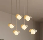 Lampa wisząca Ritual 6xG9 w kolorze mokka, składająca się z sześciu okrągłych kloszy z delikatnymi, zakrzywionymi detalami. Klosze zawieszone są na cienkich linkach, tworząc harmonijną kompozycję w minimalistycznym stylu.