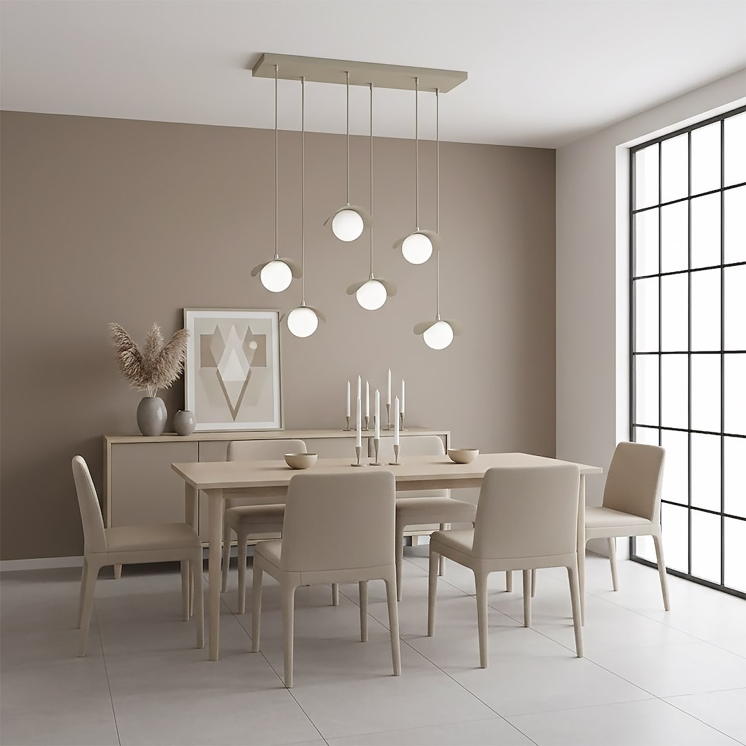 Lampa wisząca Ritual 6xG9 w kolorze mokka z sześcioma okrągłymi kloszami, zawieszona na prostokątnej podstawie. Ujęcie z góry w nowoczesnej jadalni, z drewnianym stołem i jasnymi krzesłami. Tło w odcieniach beżu, z oknem i dekoracjami na komodzie.