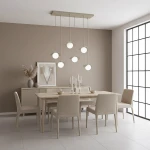 Lampa wisząca Ritual 6xG9 w kolorze mokka z sześcioma okrągłymi kloszami, zawieszona na prostokątnej podstawie. Ujęcie z góry w nowoczesnej jadalni, z drewnianym stołem i jasnymi krzesłami. Tło w odcieniach beżu, z oknem i dekoracjami na komodzie.