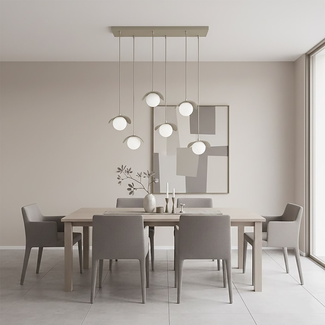 Lampa wisząca Ritual 6xG9 w kolorze mokka, zawieszona na prostokątnej podsufitce. Składa się z sześciu okrągłych kloszy z białego szkła, umieszczonych na cienkich linkach, oświetlających nowoczesną jadalnię z drewnianym stołem i szarymi krzesłami.