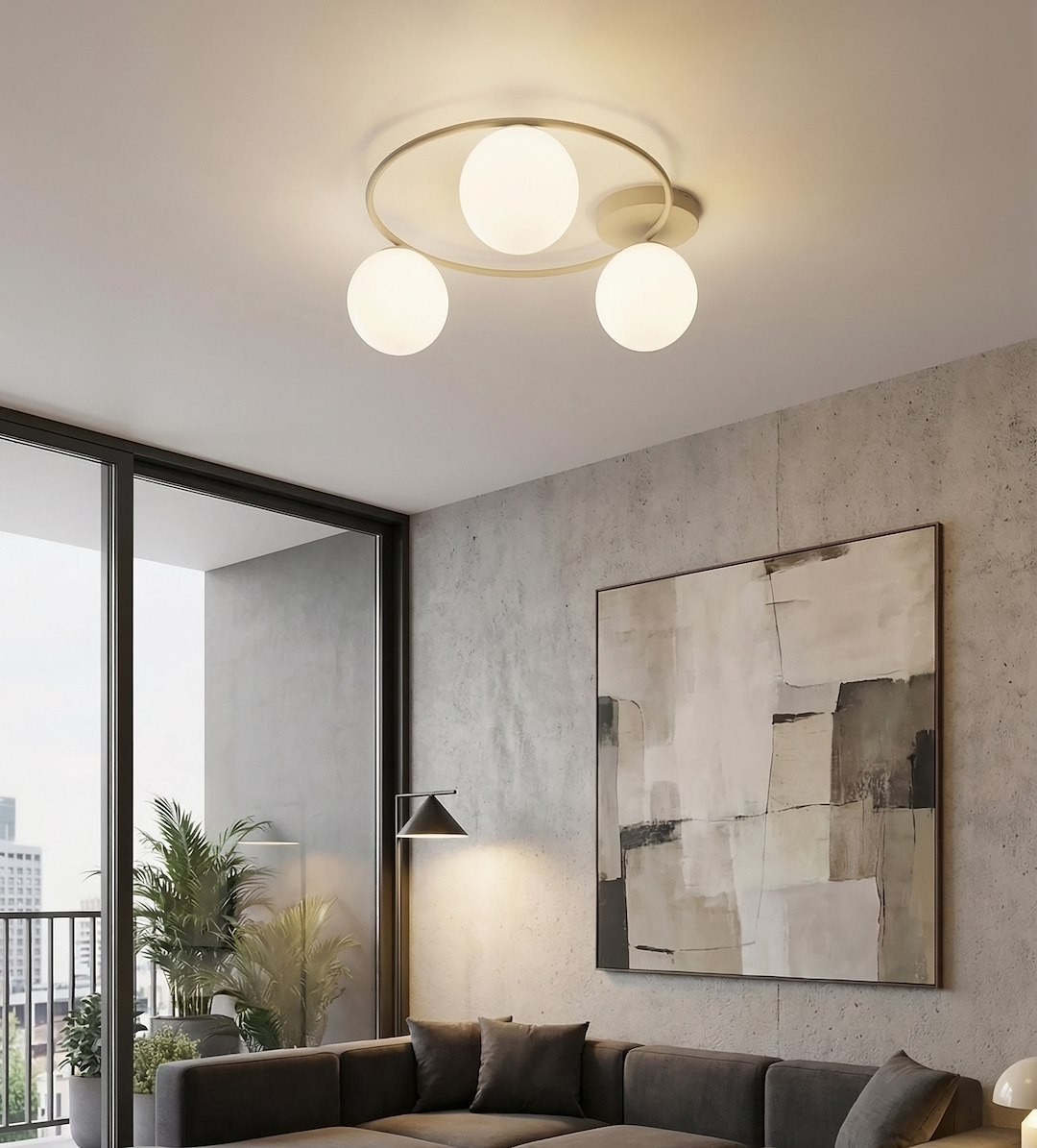Lampa sufitowa Sopra w kolorze mokka i białym, z trzema okrągłymi kloszami, zamontowana na okrągłej podstawie. Ujęcie z dołu, w nowoczesnym wnętrzu z betonową ścianą i dużymi oknami. W tle widoczna kanapa i obraz na ścianie.