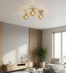 Lampa sufitowa Sopra z trzema kloszami w kolorze bursztynowym, zamocowana na okrągłej podstawie w odcieniu mokka. Klosze są szklane, półprzezroczyste, co podkreśla nowoczesny design. Produkt zawieszony na suficie w jasnym wnętrzu.