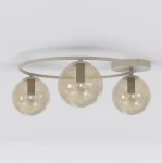 Lampa sufitowa Sopra w kolorze mokka z trzema kulistymi kloszami w odcieniu bursztynowym. Konstrukcja z metalowego pierścienia, zawieszona na suficie, z widocznymi oprawkami E14. Prosta, nowoczesna forma. Tło neutralne, jasne.