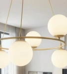 Lampa wisząca Azura w kolorze mokka i białym, składająca się z sześciu okrągłych, matowych kloszy umieszczonych na złotej obręczy. Widok z dołu, z delikatnym tłem, ukazującym nowoczesny design i eleganckie wykończenie.