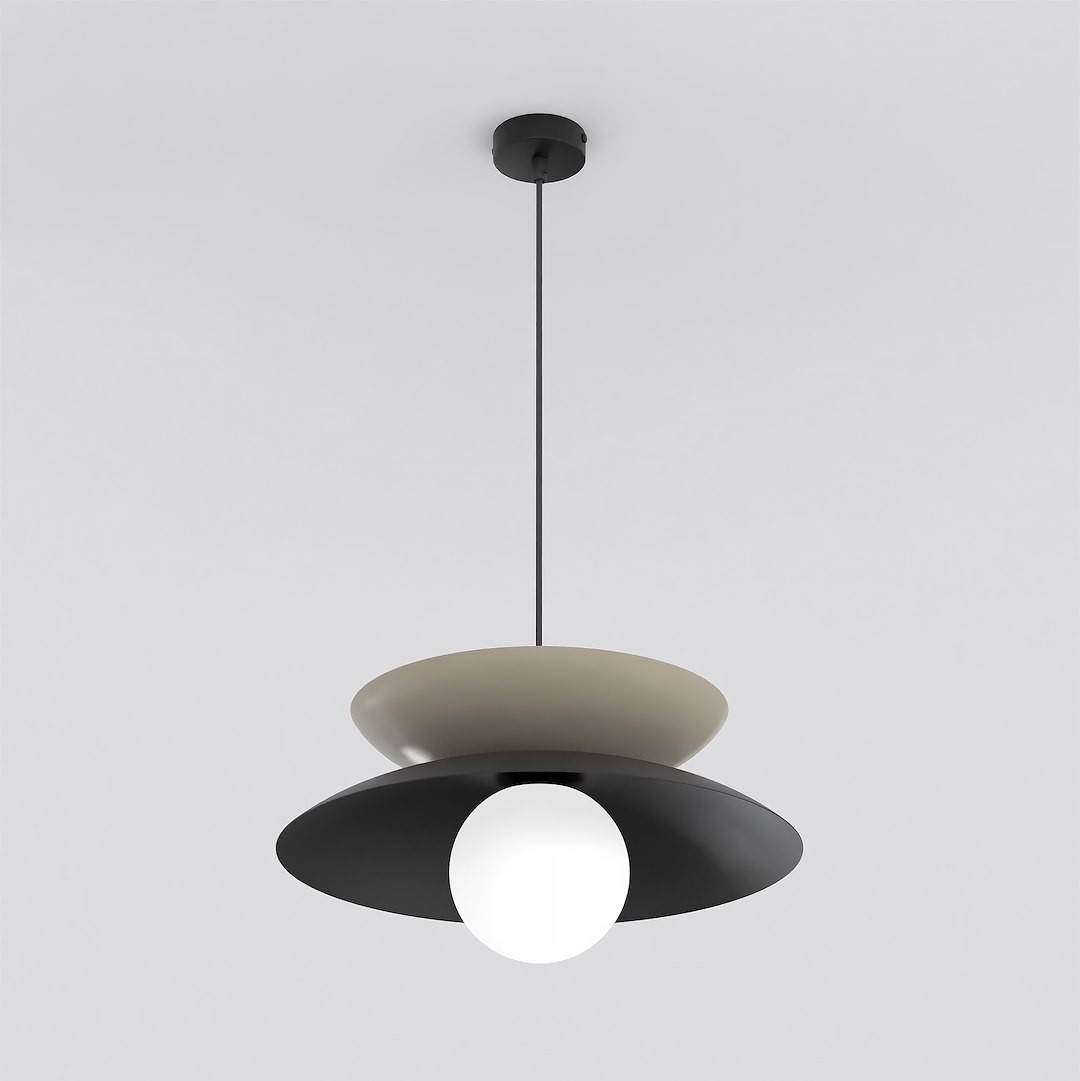 Lampa wisząca Nagoya 1xG9 w kolorze czarnym i mokka. Posiada okrągły klosz z matowego czarnego metalu oraz dolny biały klosz, zawieszona na cienkim czarnym przewodzie. Stylowe połączenie kolorów, idealna do nowoczesnych wnętrz.