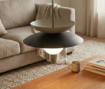 Lampa wisząca Nagoya 1xG9 w kolorze czarnym i mokka z okrągłym kloszem. Zawieszona na cienkim przewodzie, z widocznym źródłem światła. W tle jasna kanapa i stół z książkami oraz filiżanką.