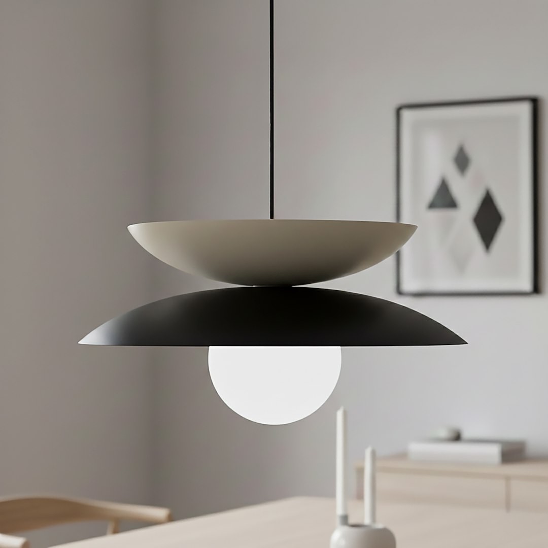 Lampa wisząca Nagoya 1xG9 w kolorze czarnym i mokka, z dwoma talerzami w różnych kolorach i okrągłą, białą żarówką. Zawieszona na cienkim przewodzie, w minimalistycznym wnętrzu.