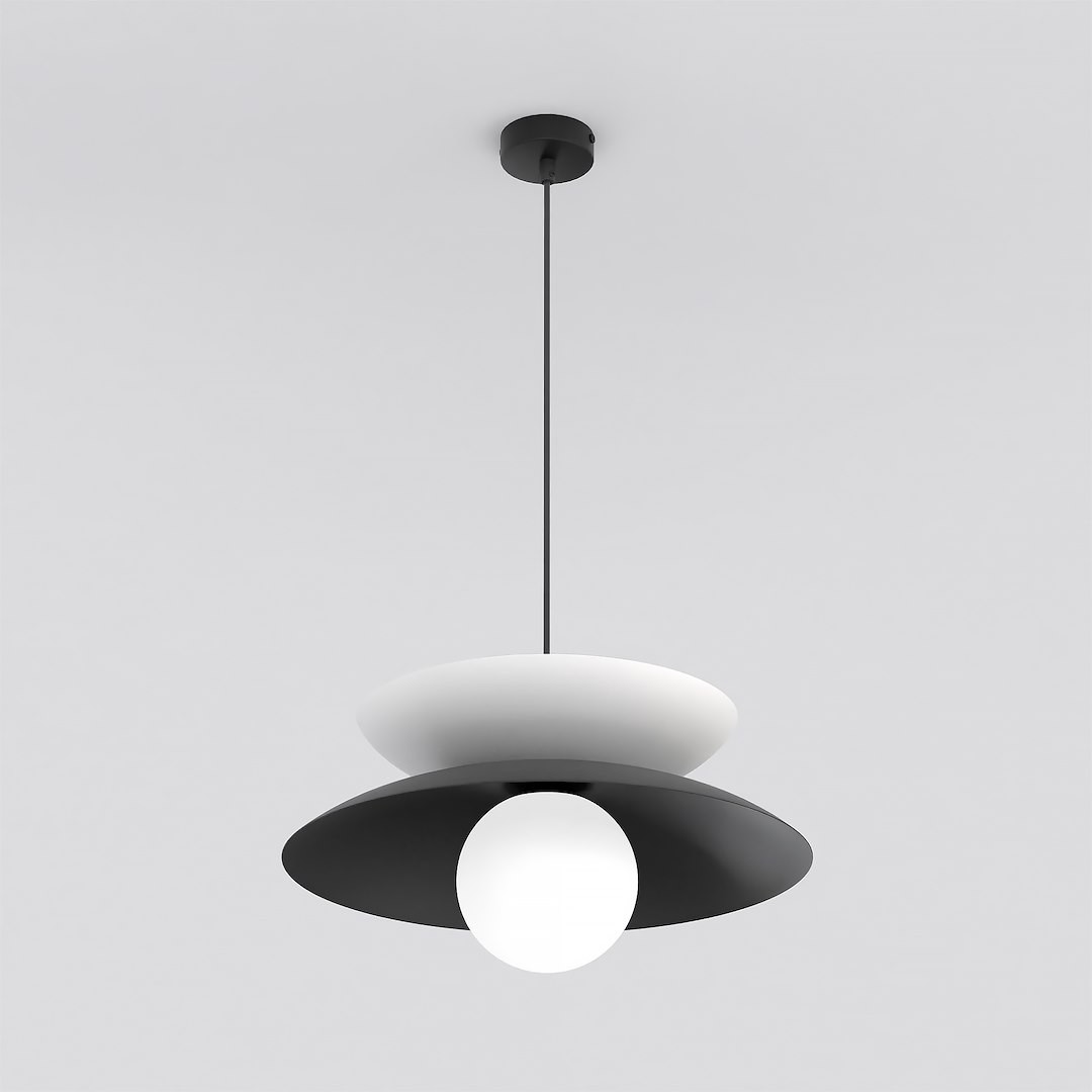 Lampa wisząca Nagoya 1xG9 w kolorze czarnym i białym, z okrągłą, białą kulą u podstawy oraz dwoma talerzowymi kloszami w kontrastowych kolorach. Zawieszona na smukłym, czarnym przewodzie, montowana do sufitu.