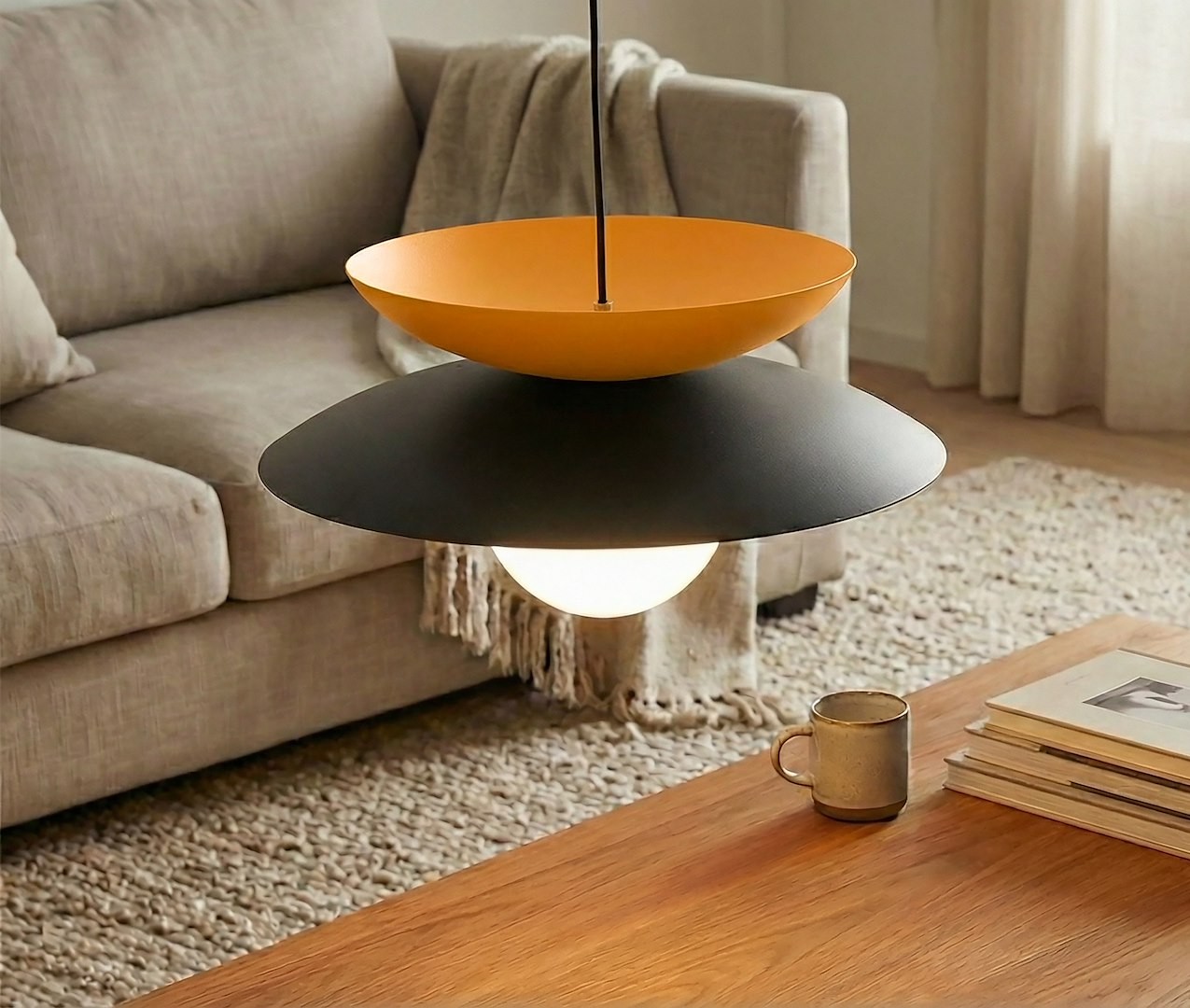 Lampa wisząca Nagoya 1xG9 w kolorze czarnym i pomarańczowym. Posiada okrągłe, pomarańczowe klosze nad czarnym, metalowym pierścieniem, z białą żarówką w centralnej części. Zawieszona nad drewnianym stołem w jasnym wnętrzu.