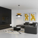 Lampa wisząca Nagoya 1xG9 w czarno-pomarańczowej kolorystyce, z okrągłą, białą żarówką. Zawieszona na czarnym przewodzie w minimalistycznym wnętrzu z szarym narożnikiem, czarnym stolikiem i dekoracyjnymi obrazami na ścianie.