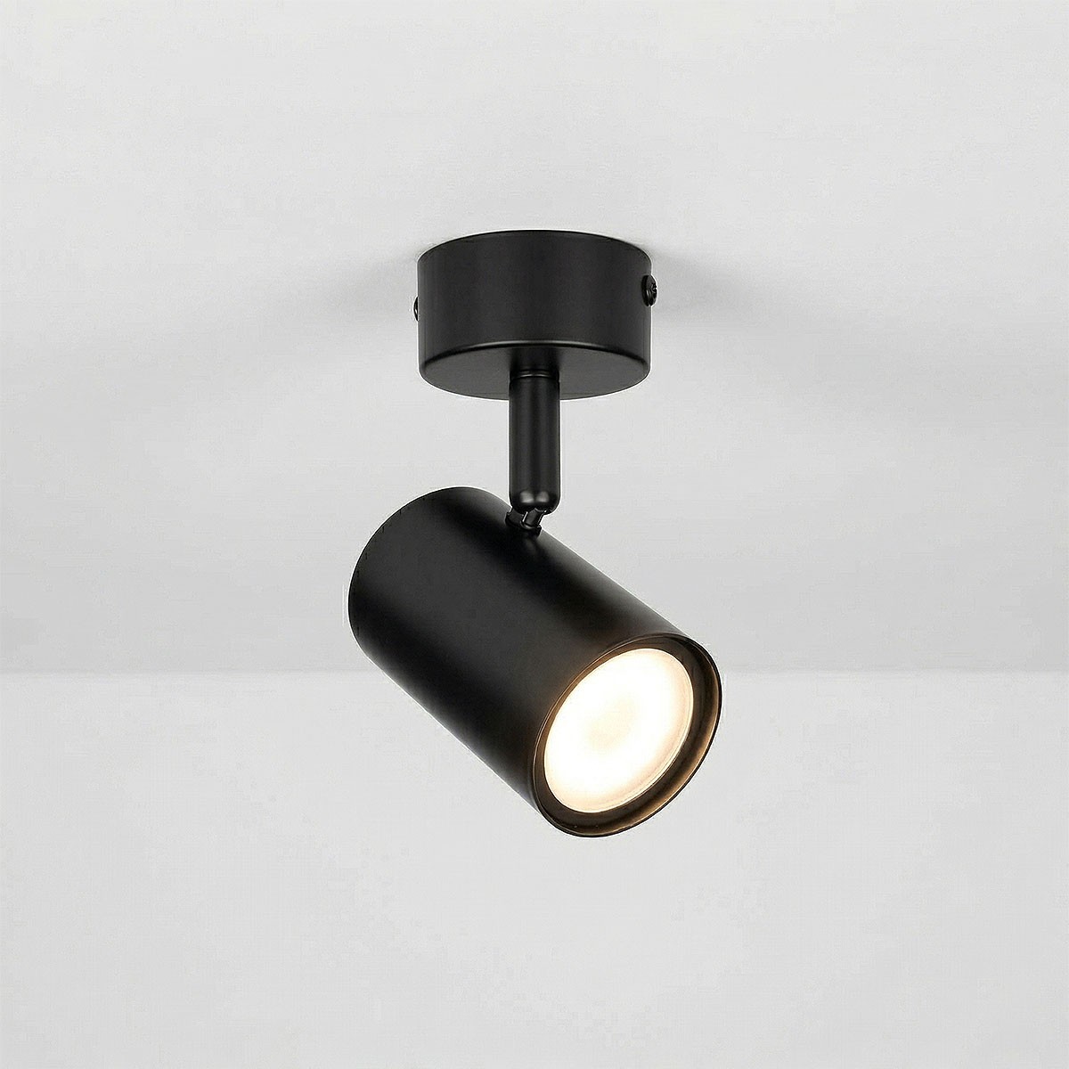 Czarna lampa sufitowa spot GU10 zawieszona pod kątem, z cylindryczną obudową i widocznym źródłem światła. Metalowy materiał o matowej fakturze, montaż na suficie. Idealna do nowoczesnych wnętrz.