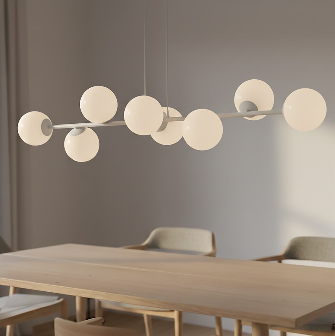 Lampa wisząca Magnus 8xE14 w kolorze szarym i białym, z ośmioma okrągłymi kloszami, zawieszona na cienkim metalowym ramieniu. Widok z góry, w kontekście stołu, na tle jednolitej ściany. Idealna do nowoczesnych wnętrz.
