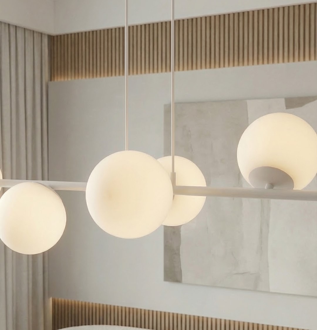 Lampa wisząca Magnus w kolorze szaro-białym z ośmioma kulistymi kloszami. Klosze mają matową powierzchnię i są zawieszone na prostym, białym stelażu. Produkt prezentowany w nowoczesnym wnętrzu z jasnym tłem i drewnianymi akcentami.