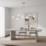 Lampa wisząca Magnus w kolorze mokka i białym, z ośmioma kulistymi kloszami na cienkich ramionach. Zawieszona nad prostokątnym, betonowym stołem w jasnym wnętrzu, obok drewnianych krzeseł i dekoracyjnej wazonu.