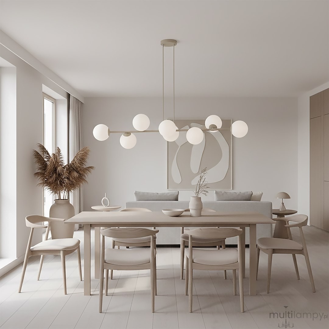 Lampa wisząca Magnus w kolorze mokka i białym, z ośmioma okrągłymi kloszami, zawieszona nad stołem w jasnym wnętrzu. Klosze wykonane z matowego szkła, lampa ma prostą, metalową konstrukcję. W tle widoczna kanapa oraz roślinność.