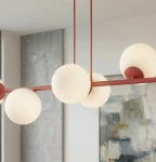 Lampa wisząca Magnus z metalowym stelażem w kolorze burgundowym, z ośmioma białymi, okrągłymi kloszami z matowego szkła. Ujęcie z góry, wisząca nad nowoczesnym wnętrzem.