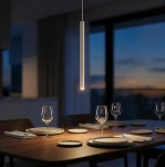 Lampa wisząca Selter 1xG9 w kolorze mokka, w formie wąskiego, prostokątnego klosza, zawieszona nad drewnianym stołem. W tle widać szklane kieliszki i talerze, a przez okno wpada wieczorne światło.
