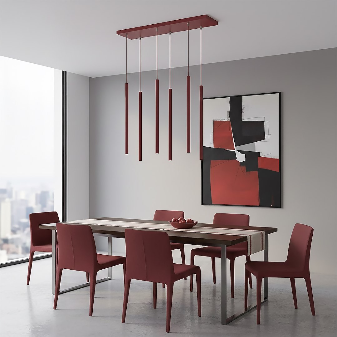 Lampa wisząca Selter 6xG9 w kolorze burgundowym, z sześcioma długimi, cylindrycznymi źródłami światła zwisającymi z prostokątnej podstawy. Umieszczona nad drewnianym stołem w nowoczesnej jadalni z burgundowymi krzesłami. Tło w jasnym odcieniu szarości.