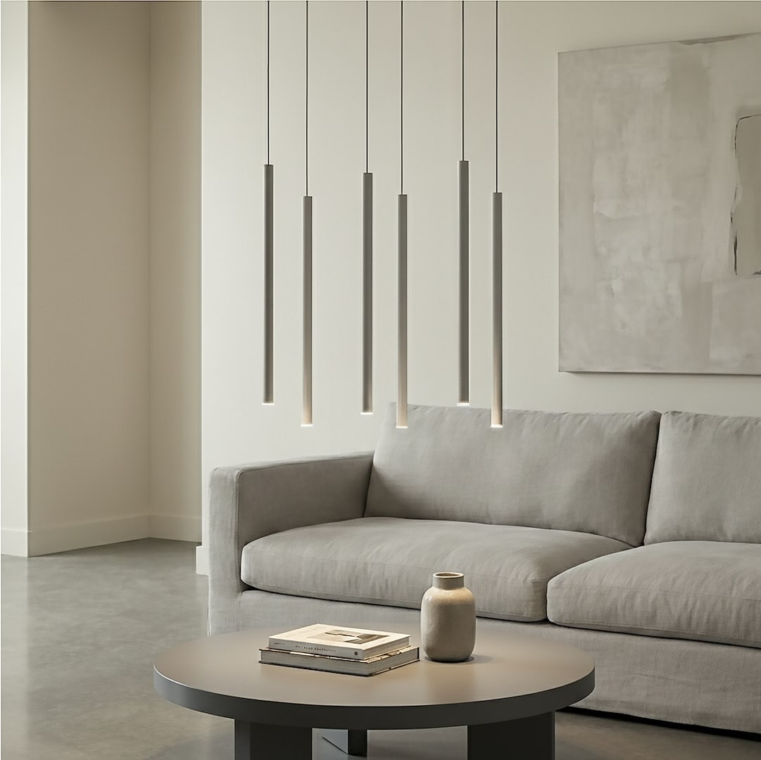 Lampa wisząca Selter 6xG9 w kolorze szarym, składająca się z sześciu prostokątnych, wiszących elementów, umieszczona nad okrągłym stołem. W tle szara tapicerka sofy i minimalistyczne wnętrze.