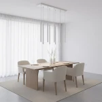 Lampa wisząca Selter 9xG9 w kolorze szarym, zawieszona na długich linkach, umieszczona nad drewnianym stołem w jadalni. W tle białe zasłony i nowoczesne krzesła w jasnym kolorze, całość w minimalistycznym wnętrzu.
