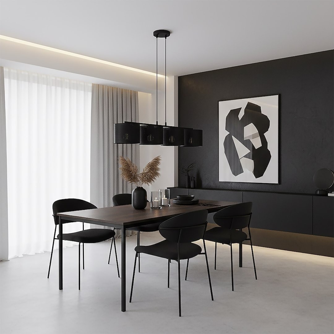 Lampa wisząca Lux 4xE27 w kolorze czarnym, zawieszona nad drewnianym stołem w eleganckiej jadalni. Posiada cztery cylindryczne klosze z dekoracyjnym wzorem. W tle widoczne minimalistyczne meble oraz abstrakcyjny obraz na ścianie.