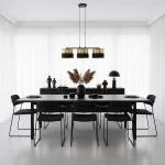 Lampa wisząca Lux 3xE27 w kolorze czarnym z złotymi akcentami, zawieszona nad prostokątnym stołem w nowoczesnej jadalni. Trzy cylindryczne klosze, minimalistyczny design, otoczenie w stonowanej kolorystyce.