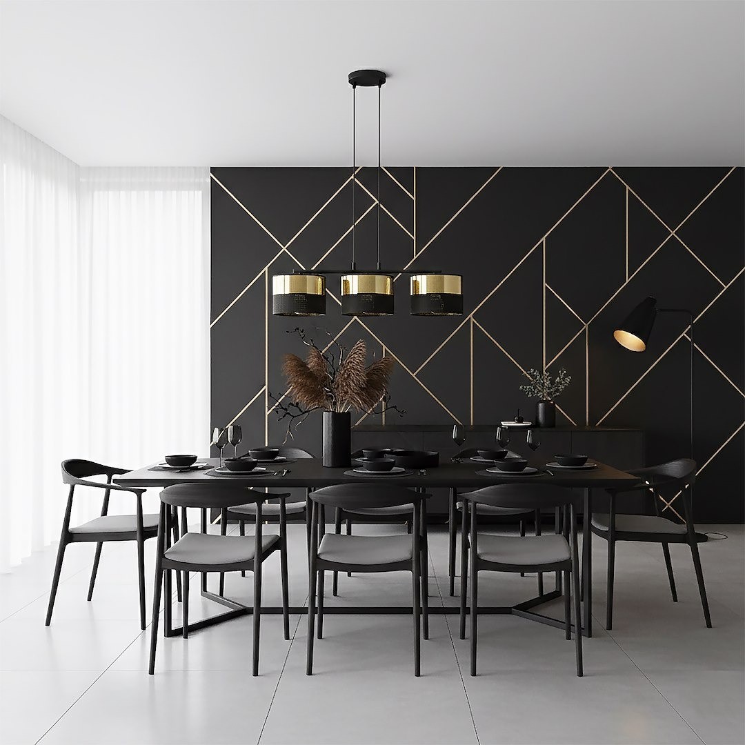 Lampa wisząca Lux 3xE27 w kolorze czarnym z złotymi kloszami, zawieszona nad czarnym stołem w eleganckiej jadalni. W tle czarna ściana z geometrycznym wzorem oraz białe zasłony. Stół nakryty czarną zastawą.