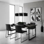 Lampa wisząca Karbon 3xE27 w kolorze czarnym, z okrągłymi kloszami, zawieszona nad ciemnym stołem w nowoczesnej jadalni. W tle widoczne okna oraz minimalistyczne grafiki na ścianie. Meble w odcieniach czerni i szarości.