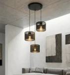 Lampa wisząca Karbon 3xE27 w kolorze czarnym z trzema kloszami w formie siatki, zawieszona na długich linkach, umieszczona w nowoczesnym wnętrzu z jasnymi ścianami i szaro-beżową sofą.