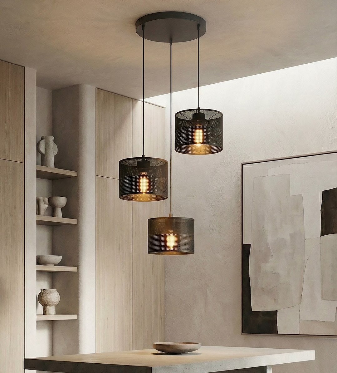 Czarna lampa wisząca Karbon z trzema żarówkami E27, z metalowymi kloszami w siatkowym wzorze. Zawieszona na długich przewodach, umiejscowiona nad stołem w nowoczesnym wnętrzu. Widoczne drewniane elementy oraz minimalistyczne dekoracje w tle.