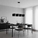 Czarna lampa wisząca Karbon 4xE27 z metalowymi kloszami, zawieszona na długich linkach, umieszczona nad stołem w nowoczesnej jadalni. Tło w odcieniach szarości, z minimalistycznymi dekoracjami i jasnymi firanami.