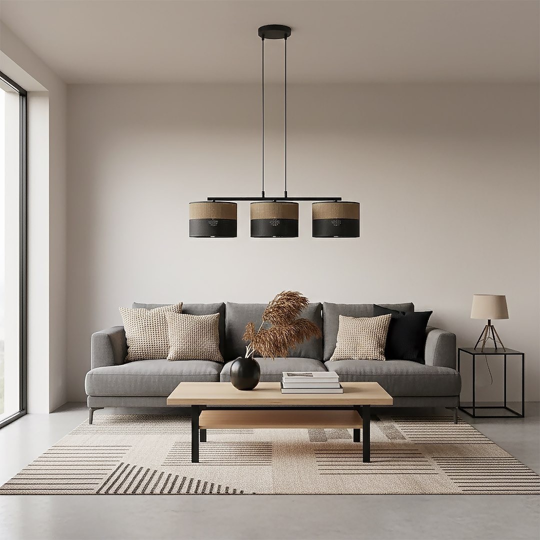 Lampa wisząca Karbon 3xE27 w kolorze czarnym i brązowym, z trzema okrągłymi kloszami, zawieszona nad stolikiem w nowoczesnym wnętrzu. Ułożona na tle szarej kanapy i jasnej podłogi, otoczona dekoracjami i roślinami.