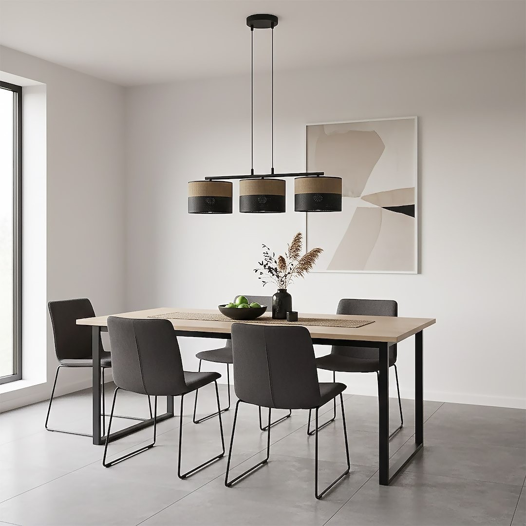 Lampa wisząca Karbon 3xE27 w kolorze czarnym i brązowym, z trzema kloszami na metalowej konstrukcji, zawieszona nad drewnianym stołem w jadalni. W tle widoczna ściana z oknem i obrazem. Fotele w odcieniach szarości.