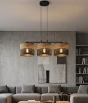 Lampa wisząca Karbon z trzema kloszami E27, w kolorze czarnym i brązowym, zawieszona na długich linkach. Klosze mają ażurową strukturę, tworząc efektowną grę światła. Produkt umieszczony nad szarym narożnikiem, w nowoczesnym wnętrzu.