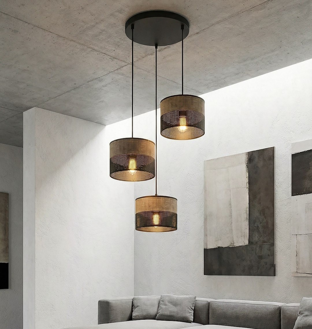 Lampa wisząca Karbon z trzema abażurami w odcieniach czerni i brązu, zawieszona na cienkich linkach z sufitu. Abażury mają perforowaną strukturę, a wewnątrz znajdują się żarówki E27, zapewniając subtelne oświetlenie w nowoczesnym wnętrzu.