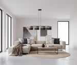 Lampa wisząca Karbon 4xE27 w kolorze czarnym i brązowym. Posiada cztery okrągłe klosze zawieszone na cienkich linkach, umieszczona nad jasnym, nowoczesnym salonem z kanapą i stołem. Tło w minimalistycznym stylu z dużymi oknami.