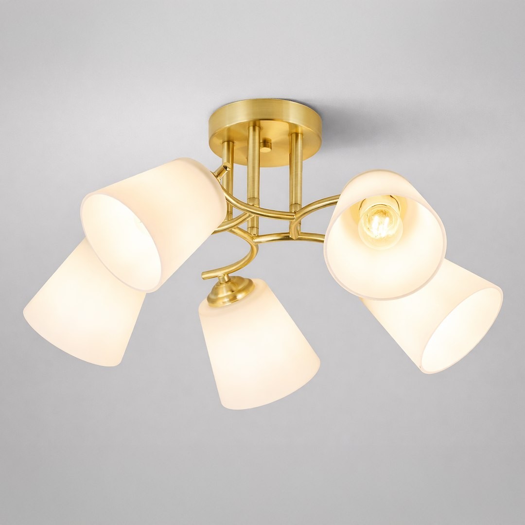 Lampa sufitowa Pafos w kolorze złotym z pięcioma kloszami w kształcie stożków w kolorze białym. Ujęcie z dołu, widoczna metalowa podstawa i żarówka w centralnym punkcie. Idealna do nowoczesnych aranżacji wnętrz.