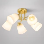 Lampa sufitowa Pafos w kolorze złotym z pięcioma kloszami w kształcie stożków w kolorze białym. Ujęcie z dołu, widoczna metalowa podstawa i żarówka w centralnym punkcie. Idealna do nowoczesnych aranżacji wnętrz.