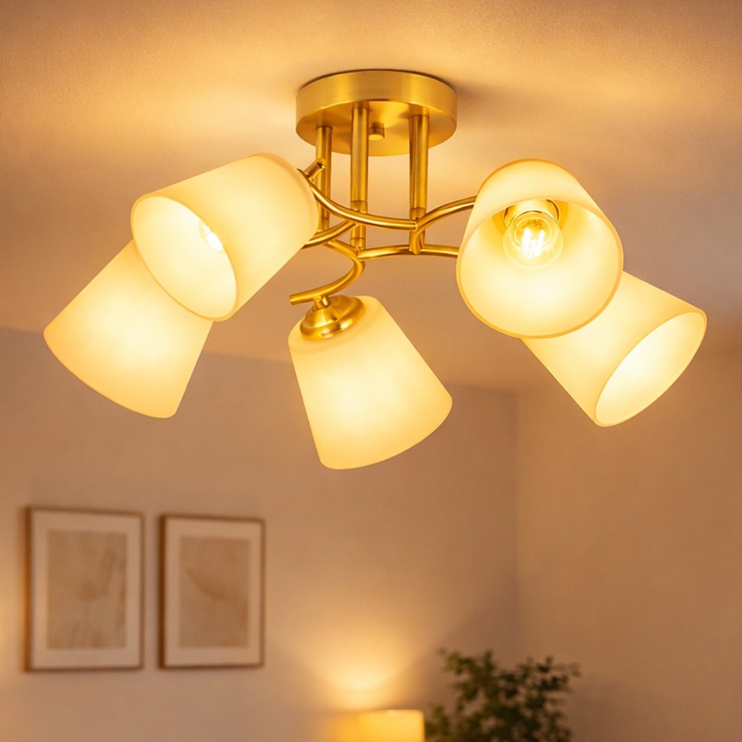 Lampa sufitowa Pafos z pięcioma kloszami w kolorze złotym, z materiału matowego, zamontowana na okrągłej podstawie. Klosze mają lekko stożkowaty kształt, skierowane w różnych kierunkach. Tło jasne, z subtelnym oświetleniem w pomieszczeniu.