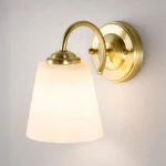 Kinkiet Pafos 1xE27 w kolorze złotym, z lekko zaokrąglonym kloszem z mlecznego szkła. Uchwyt ma elegancką, metalową konstrukcję z delikatnym wygięciem, zamontowany na okrągłej podstawie. Idealny do nowoczesnych wnętrz.