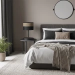 Lampka stołowa Karbon E27 w kolorze czarnym z brązowym abażurem, umieszczona na okrągłym stoliku obok łóżka w nowoczesnej sypialni. Tło w neutralnych odcieniach, z rośliną w donicy oraz dekoracyjnym lustrem na ścianie.