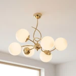 Lampa wisząca Tornado w kolorze złotym z sześcioma kulistymi kloszami z matowego szkła. Produkt zawieszony, z eleganckim, zakrzywionym ramieniem, idealny do nowoczesnych wnętrz. Wymiary i detale montażowe niewidoczne.
