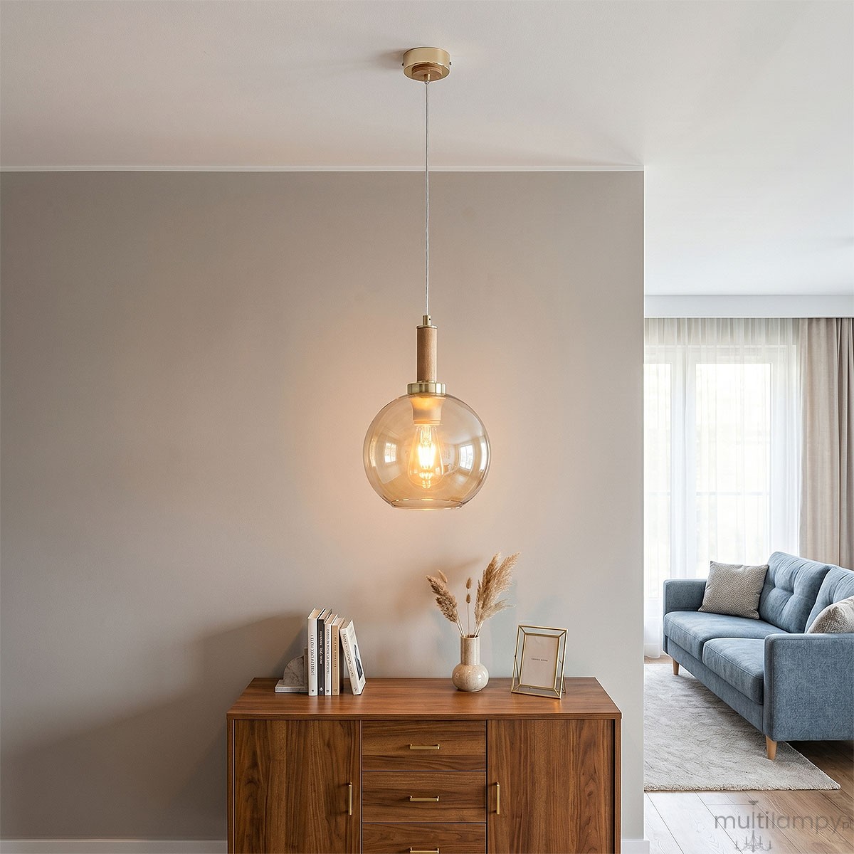 Lampa wisząca Hetty z pojedynczym gniazdem E27, w kolorze złotym i drewnianym. Okrągły klosz ze szkła w odcieniu bursztynowym, zawieszona na przezroczystym przewodzie. Stylowy element oświetleniowy idealny do nowoczesnych wnętrz.